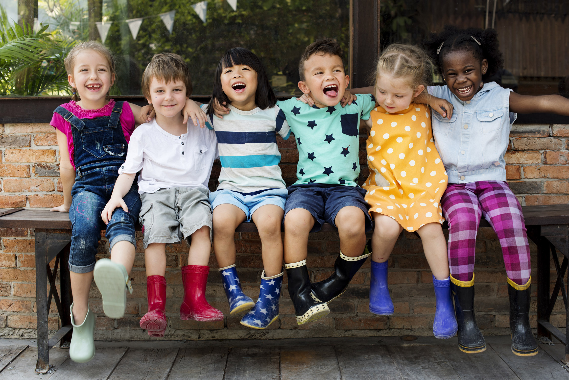 Kids sitting on a bench smiling.
