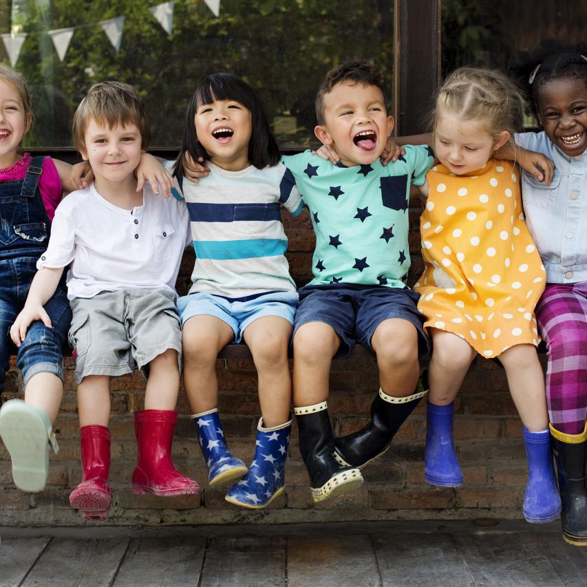 Kids sitting on a bench smiling.